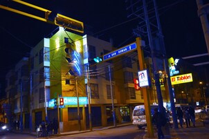 Un edificio de varios pisos con señalización iluminada, incluyendo un llamativo letrero 'Jr. San Roman' y un letrero 'Tablón Food Center'.