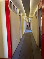 Pasillo de hotel con puertas a ambos lados, un pasillo central e iluminación empotrada en el techo.
