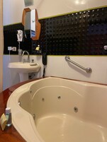 Un baño con una bañera grande, un lavabo y un espejo.