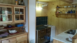 Een houten interieur met een keukenhoek, inclusief een fornuis, kastjes en een spoelbak.