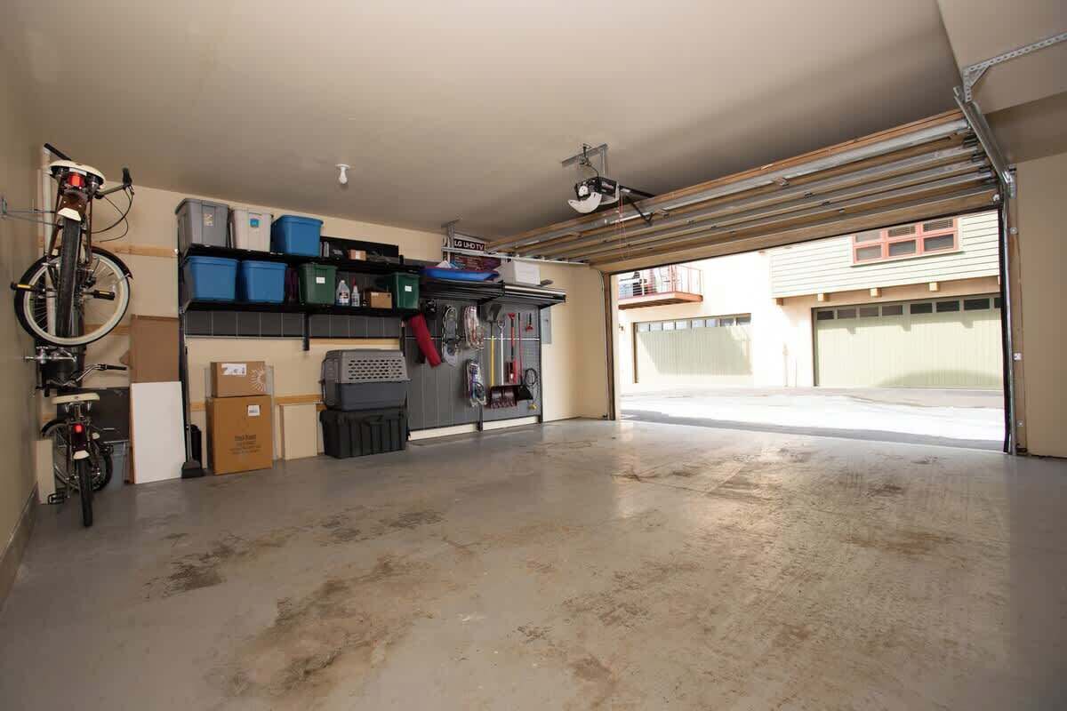 Un garage contenant un vélo, des étagères de rangement et un sol en béton.