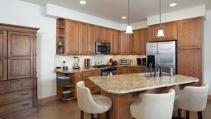 A modern kitchen with wooden cabinets, a central island with bar stools, stainless steel appliances, and pendant lighting. - Majestic Mountain Family Escape - 4 bedroom/4Bathroom with lots of room and easy access to the slopes, river and town (Steamboat Springs)