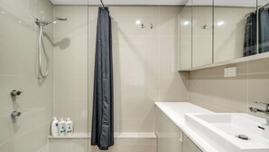 Et moderne badeværelse med bruser, håndvask og spejl.