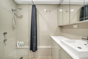 A modern bathroom with a shower, a sink, and a mirror. - 1BR unit in the heart of Manly (Manly)