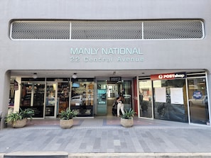 Un escaparate con el letrero 'MANLY NATIONAL 22 Central Avenue' y el rótulo 'POSTshop'.