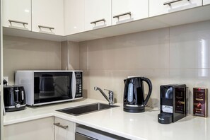 A modern kitchen with a microwave, coffee maker, and coffee machine. - 1BR unit in the heart of Manly (Manly)