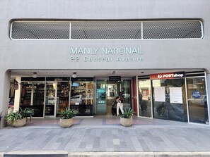 Fachada com a placa 'MANLY NATIONAL 22 Central Avenue' e a indicação 'POSTshop'.