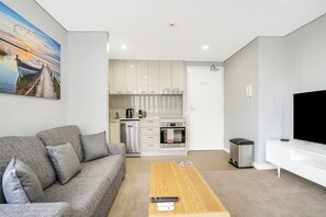 Uma sala de estar moderna com um sofá cinza, uma mesa de centro de madeira e uma televisão de tela plana.