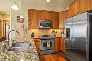 A kitchen with wooden cabinets, stainless steel appliances, granite countertops, and a built-in oven. - Majestic Park - 4 Bed/4 Bathroom with Easy Ski  and Core Trail Access (Steamboat Springs)