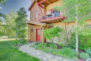 Stroll up the stone pathway to this charming home, featuring a cozy balcony and a welcoming red door.