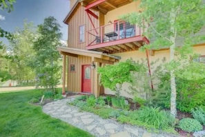 Stroll up the stone pathway to this charming home, featuring a cozy balcony and a welcoming red door.