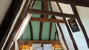 A bedroom with a sloped ceiling, wooden beams, a bed, bedside tables, and a nightstand. - "Le Pigeonnier", in the valley of the 5 castles in Périgord Noir (vezac)