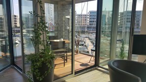 Una habitación moderna con ventanas amplias, una planta en maceta, una mesa y una silla.