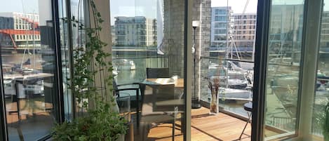 A balcony with a view of a marina, a potted plant, and a table with chairs.