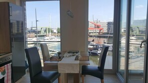 Comedor con vistas a un puerto deportivo, un refrigerador y una mesa con sillas.