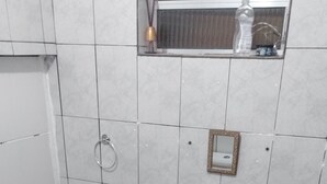 A bathroom with a white sink, a mirror, and a small shelf with a bottle. - leandrohoteis23 (Guarulhos)