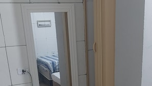 A small, narrow room with a bed, a chair, and a door leading to another room. - leandrohoteis23 (Guarulhos)