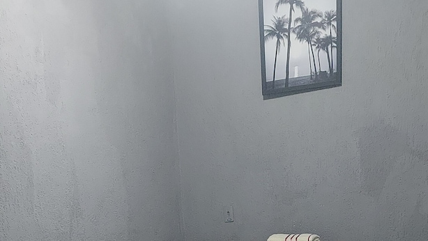 A small, dimly lit room with a single bed, a small table, and a wall-mounted picture. - leandrohoteis23 (Guarulhos)