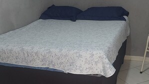 A bed with a dark frame and a patterned bedspread, a window with a view, and a tiled floor. - leandrohoteis23 (Guarulhos)
