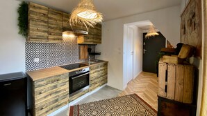 Een moderne keuken met houten kastjes, een decoratieve achterwand en een hangende lamp.