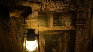 Een stenen muur met gebeeldhouwde figuren en een lichtgevende lantaarn.