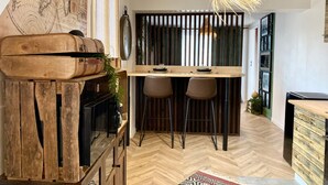 Een moderne keuken met een visgraatvloer, houten barstoelen en een hangende lamp.
