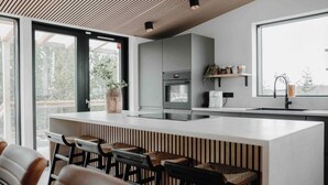 Una cocina moderna con una isla grande, taburetes de bar y vistas al exterior.