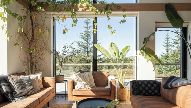 Una sala de estar moderna con un conjunto de sofá, una mesa de centro y un ventanal con vistas a zonas verdes.