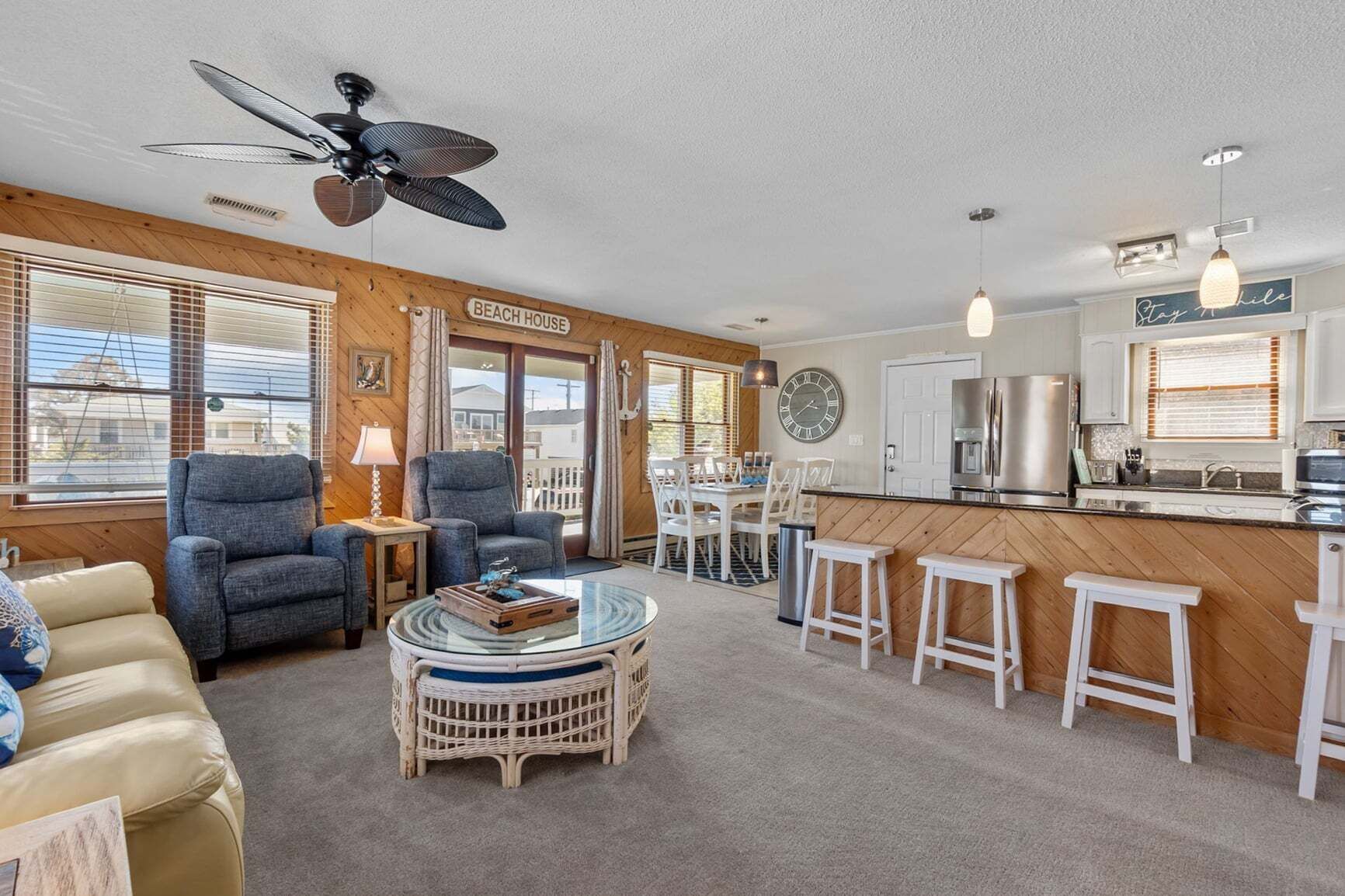 A beach house interior with a dining area, kitchen, and seating.