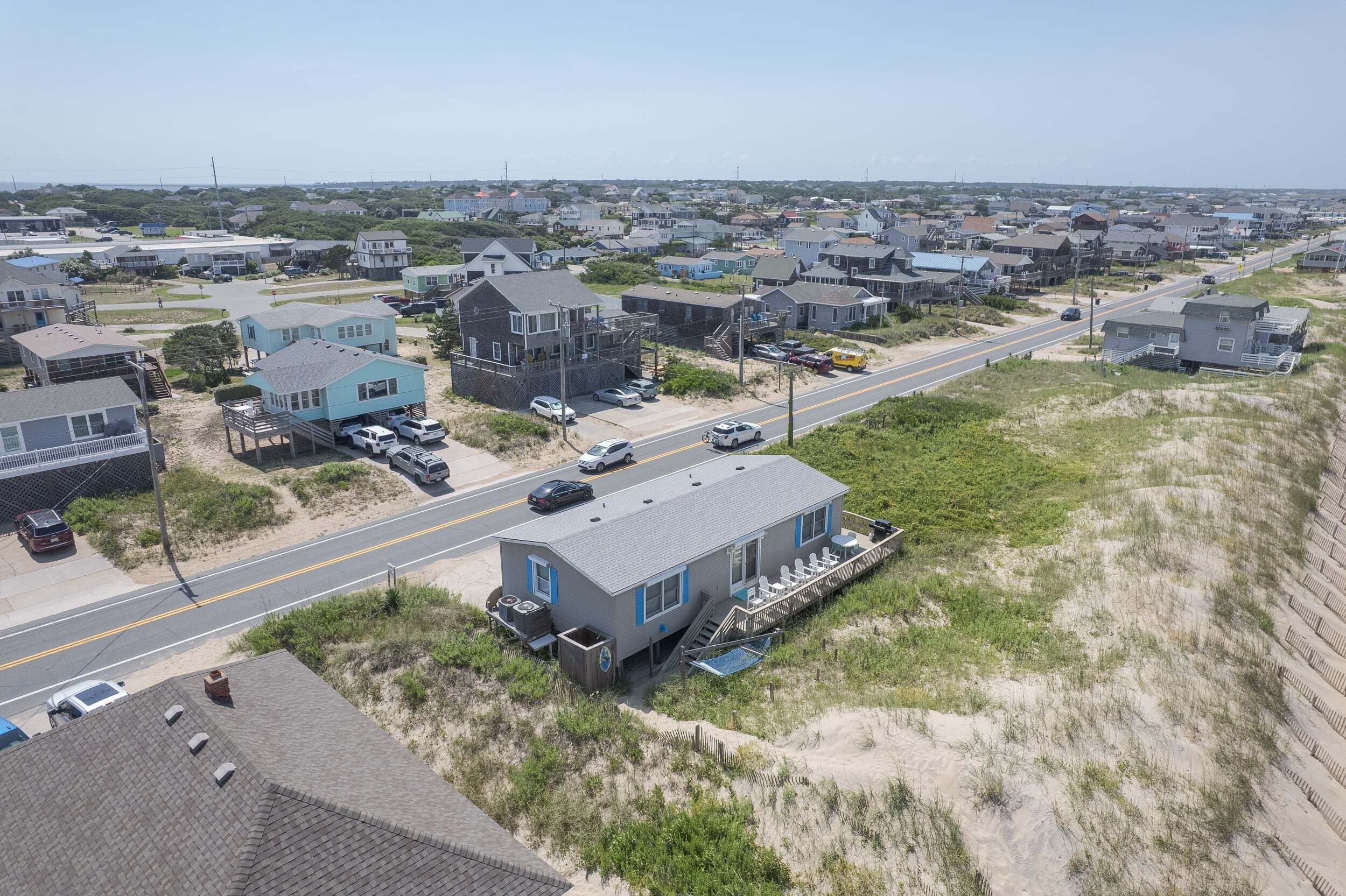 A coastal residential area with houses, a road, and a beach.