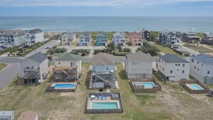 A coastal residential area with houses, a swimming pool, and a view of the ocean. - 5418- Family Tides - Semi-Oceanfront OBX Home for Large Groups (Nags Head)