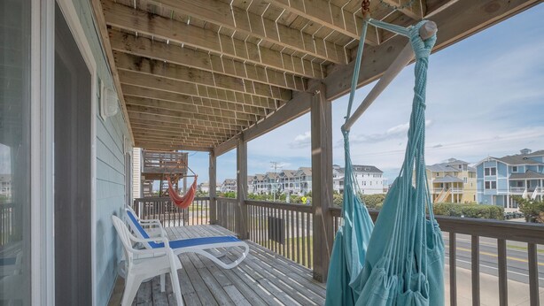 A wooden deck with a hammock and a chair, overlooking a residential area. - 5418- Family Tides - Semi-Oceanfront OBX Home for Large Groups (Nags Head)