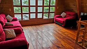 Una habitación acogedora con piso de madera, un sofá rojo y un televisor sobre un mueble de madera.