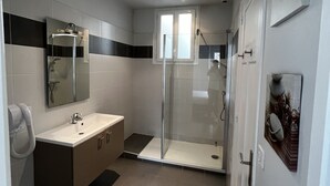 Une salle de bain moderne avec une douche à parois de verre, un lavabo avec un miroir et des toilettes.