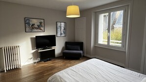 Une chambre à coucher avec un lit, une télévision, une chaise et une fenêtre.