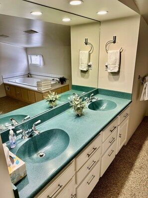 Une salle de bain avec deux lavabos, un grand miroir et une baignoire.