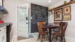 A kitchen with a chalkboard menu, wooden chairs, and a dining table.