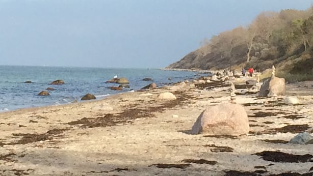 Ein felsiger Strand mit großen Felsen und freiem Blick auf das Meer.