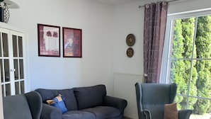Ein Wohnzimmer mit grauem Sofa, einem Glastisch und einem gemusterten Teppich.
