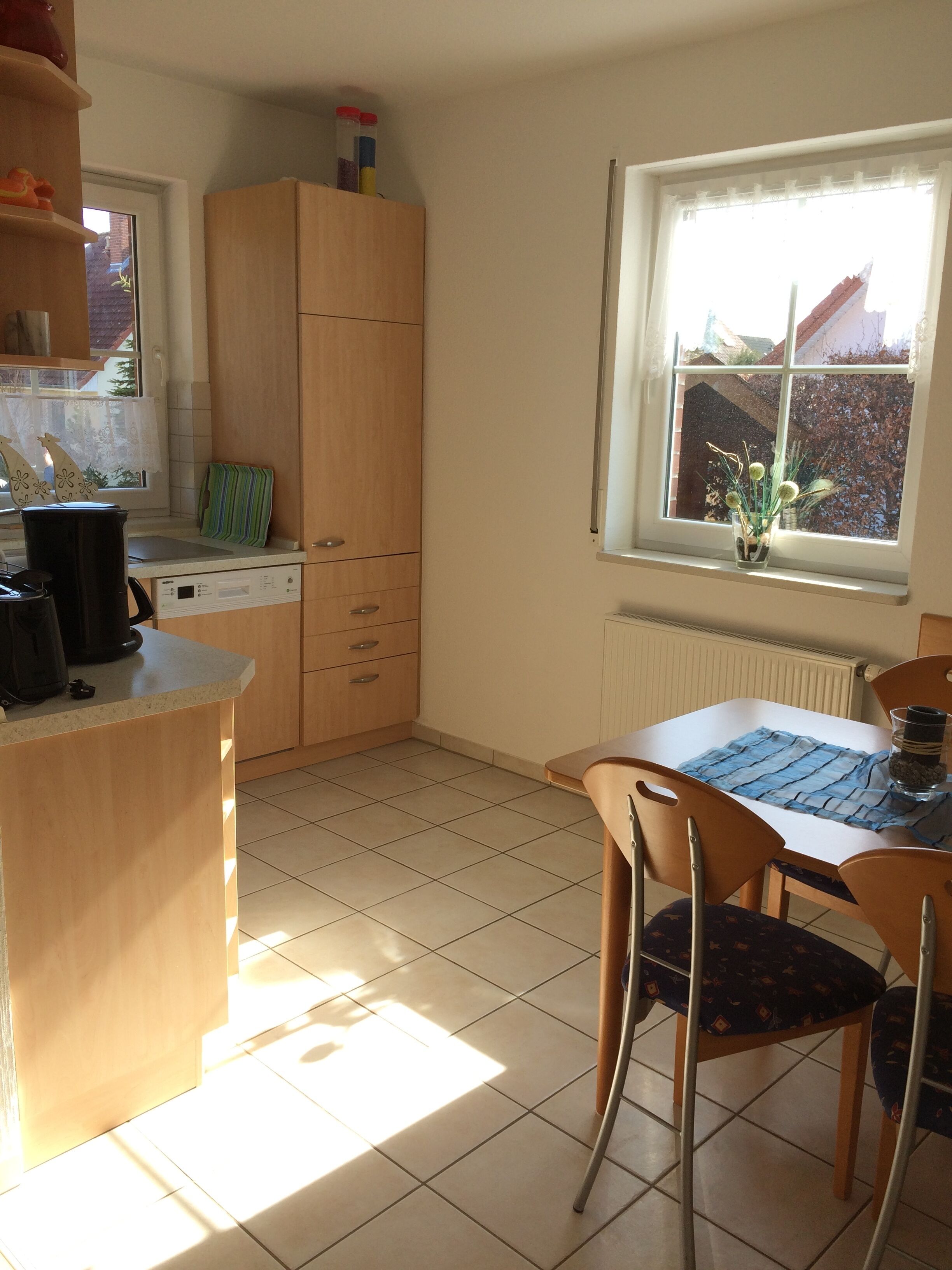 A kitchen with a window, a dining table with chairs, and a radiator.