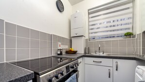 Eine moderne Küche mit einer schwarzen Kochplatte, einem Edelstahlbackofen und weißen Schränken.