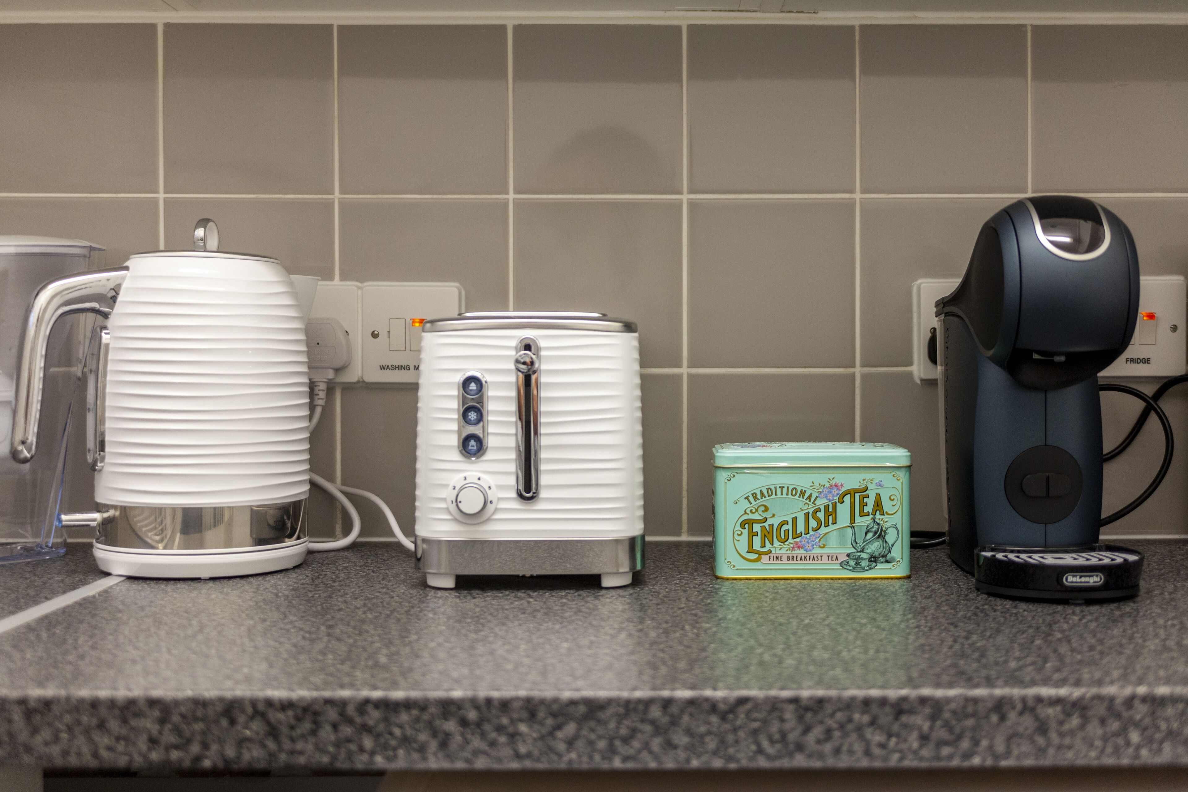 Eine Küchenarbeitsplatte mit Kaffeemaschine, Toaster, Wasserkocher und einer Teedose.