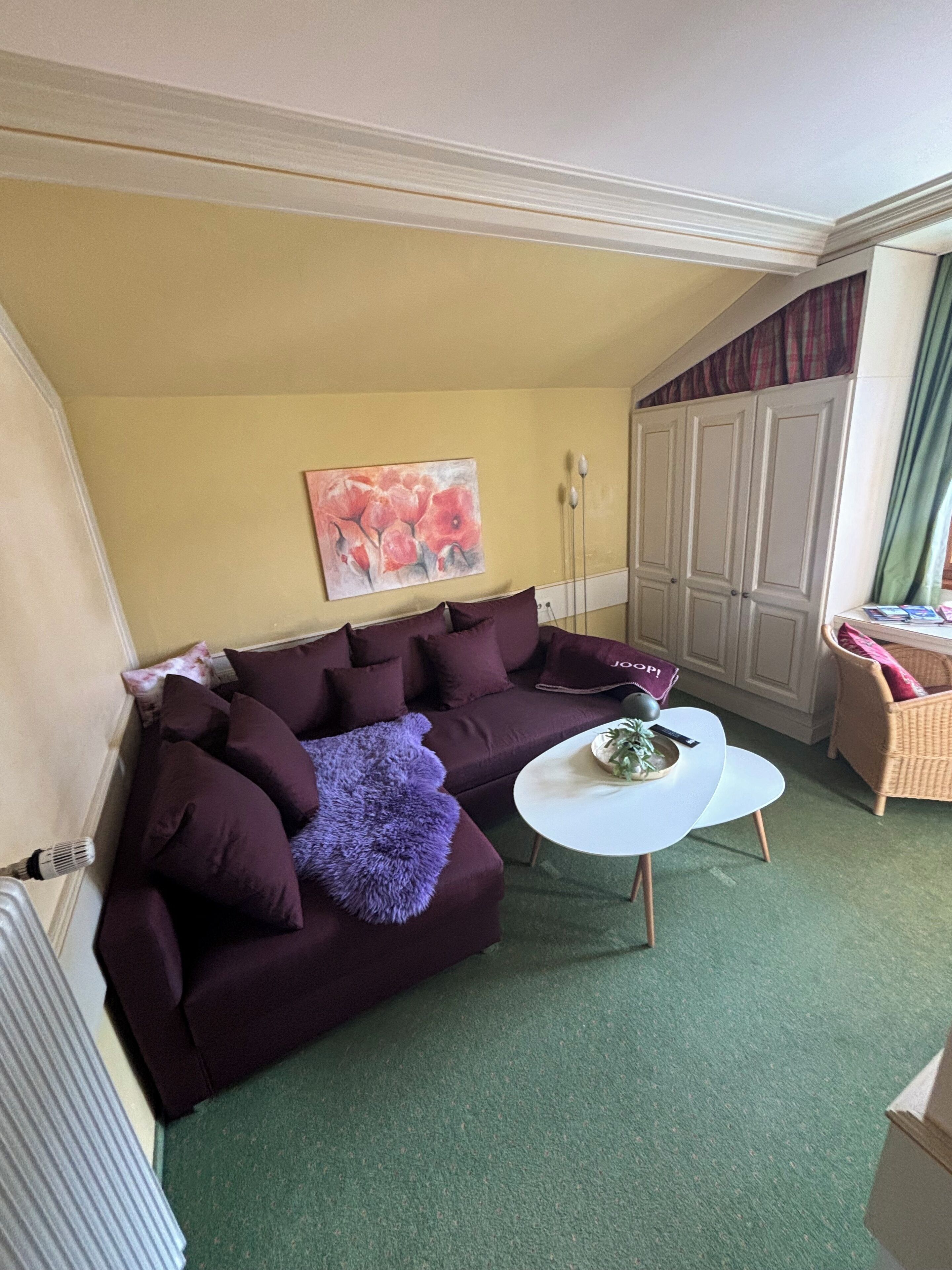 Un salon avec un canapé violet, une table basse blanche et un tableau accroché au mur.