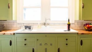 A kitchen with green cabinets, a white countertop, and a window above the sink. - The Jackson (Nashville)
