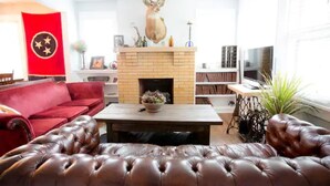 A living room with a fireplace, a red flag, a mounted deer head, a red sofa, and a leather ottoman. - The Jackson (Nashville)