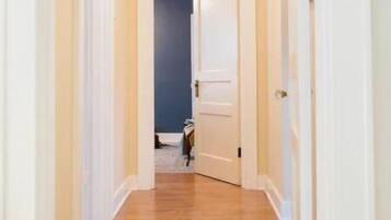 A narrow hallway with wooden flooring and white walls.