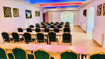 A conference room with rows of tables and chairs, a ceiling with colorful lighting, and artwork on the walls.