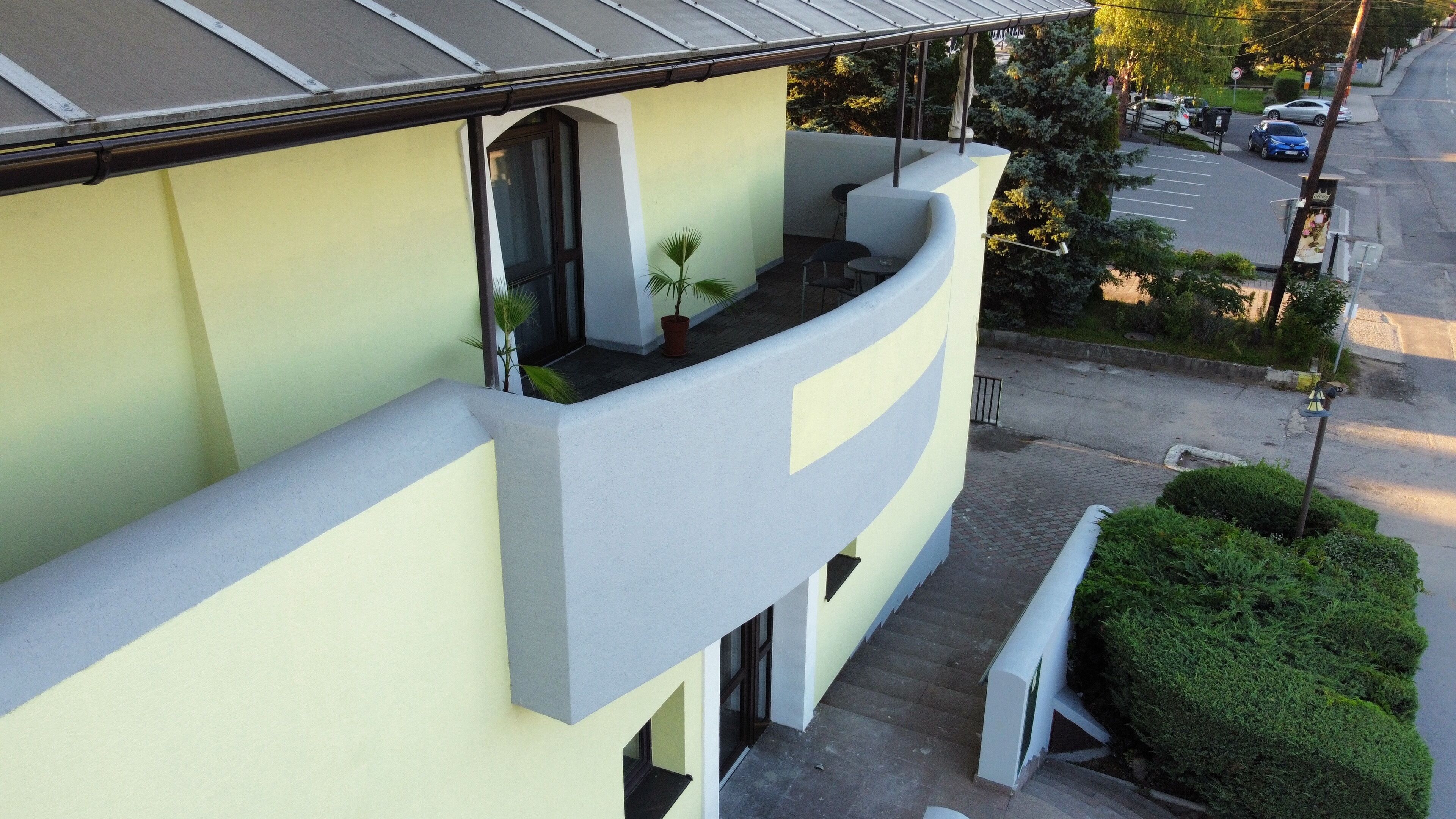 Ein modernes Gebäude mit einem gebogenen Balkon, einem kleinen Fenster und einem Blumentopf.