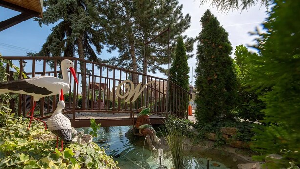 A garden with a pond, a bridge, and a statue of a swan. - WX Hotel (Bratislava)