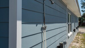 Uma casa azul com uma mangueira de metal fixada na parede externa.